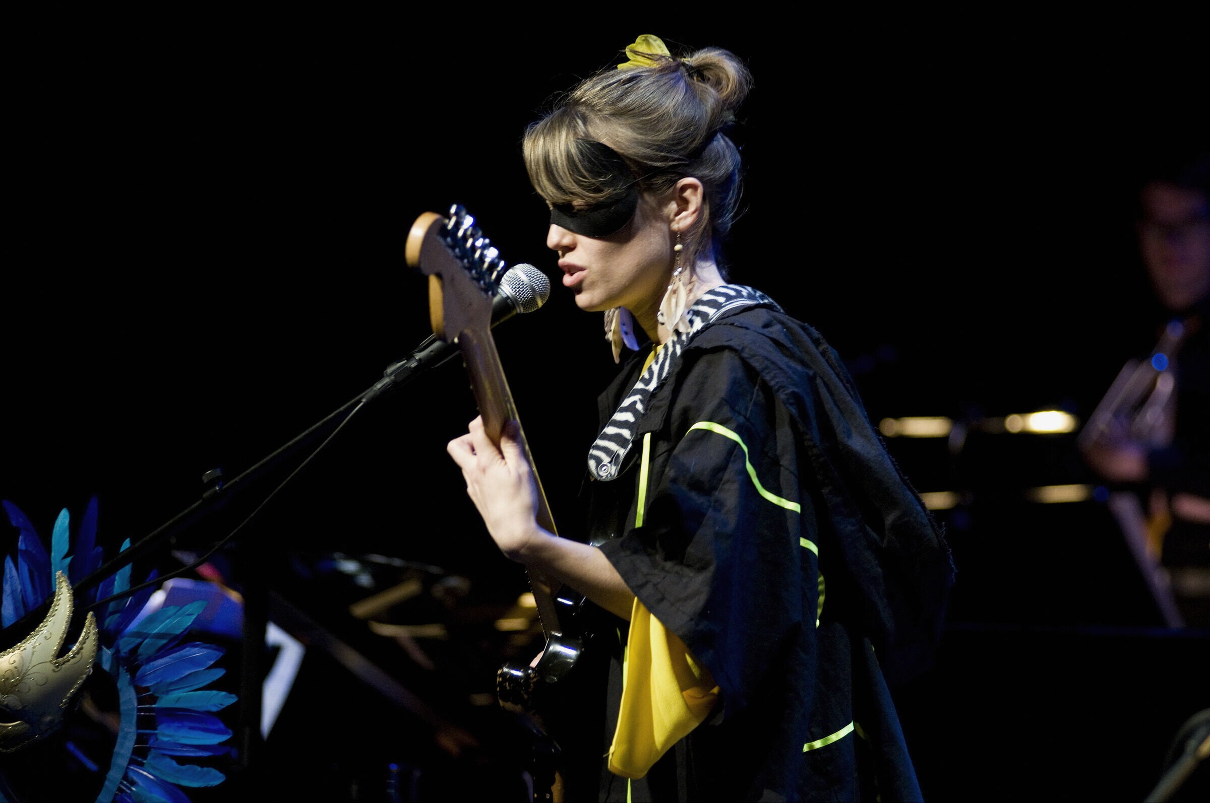 A guitarist singing at a microphone under stage light at Jazzfest Berlin.