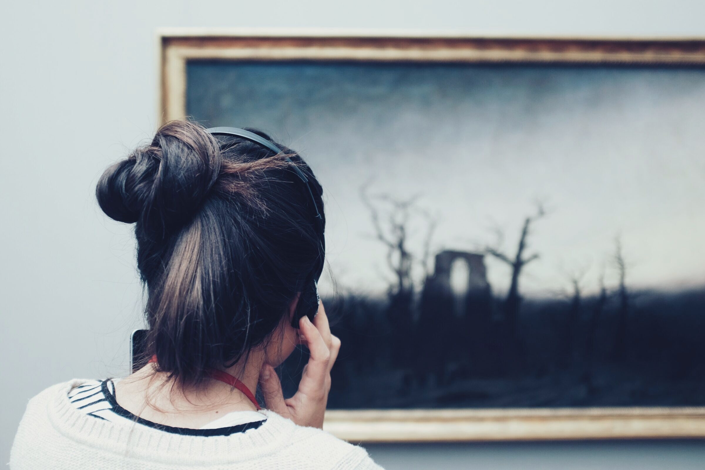 A visitor with headphones looking at a Caspar David Friedrich painting in the Alte Nationalgalerie.