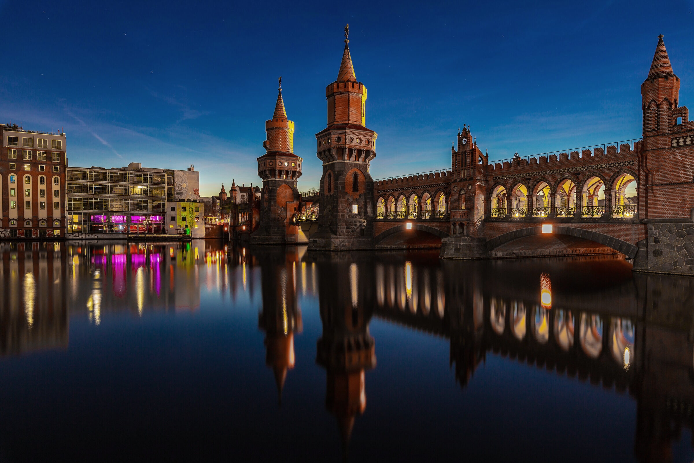 The Oberbaum bridge over the Spree at the blue hour, reflected in still water.