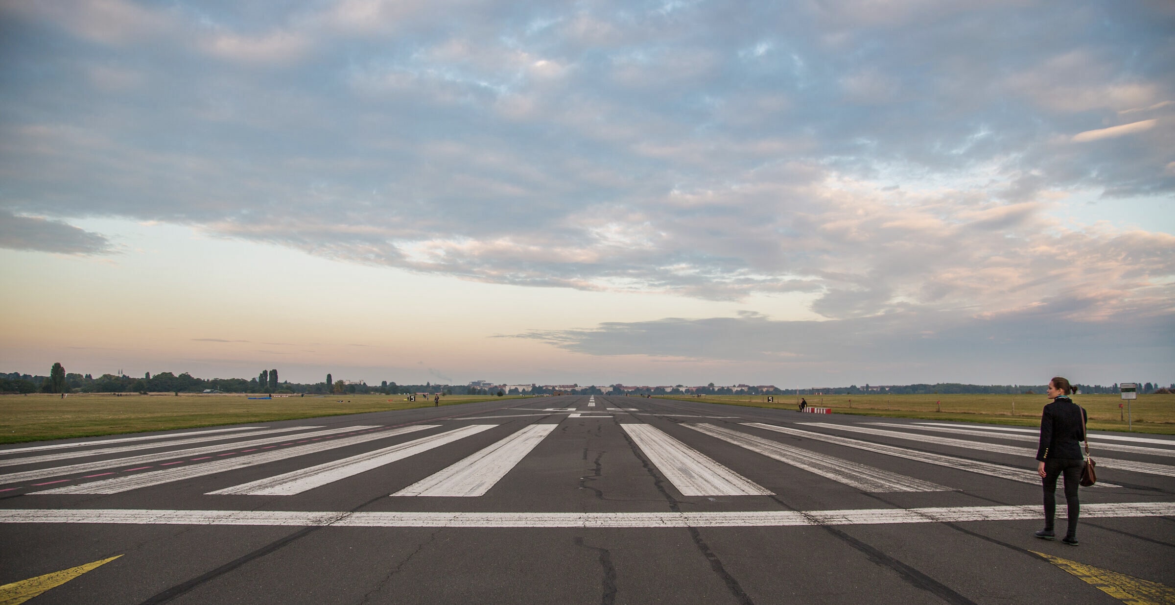 A former runway at Tempelhof, now a public park, under a wide evening sky.