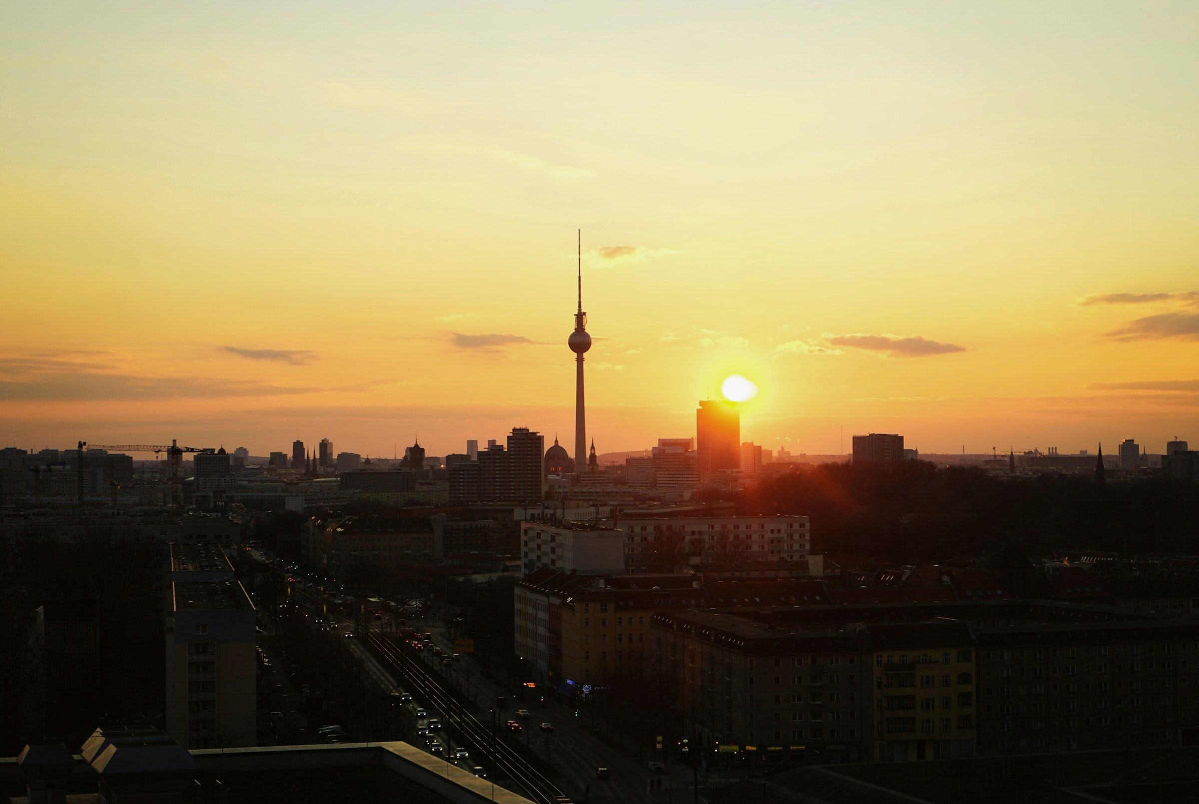 The sun clearing the Berlin skyline at dawn, the television tower in silhouette.