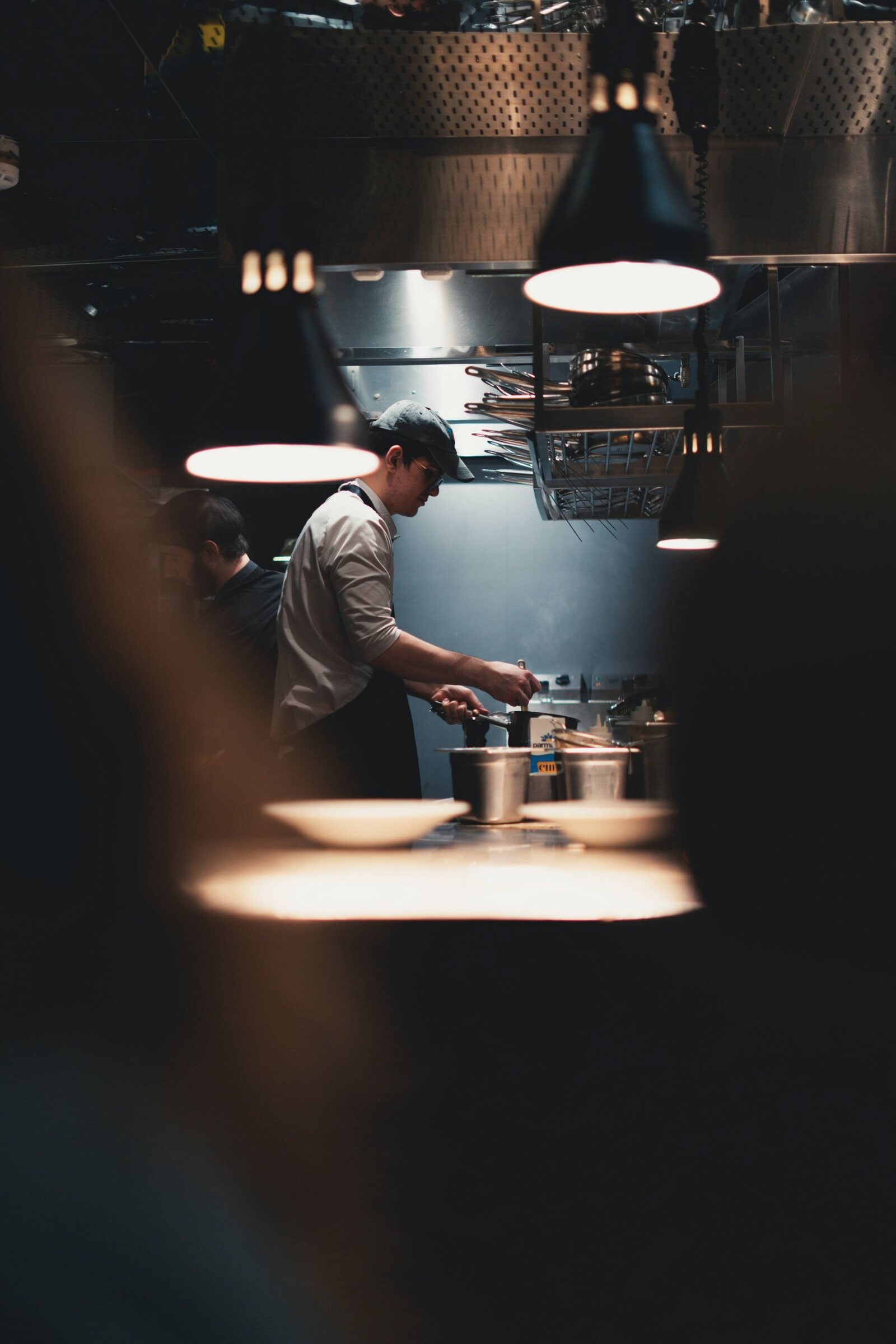 A chef alone under a spotlight in a dark kitchen.