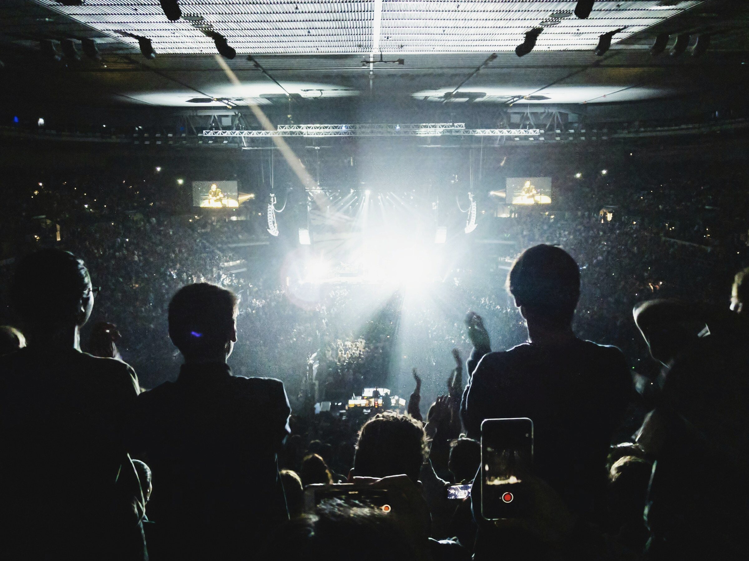 Silhouettes of an audience against stage light.