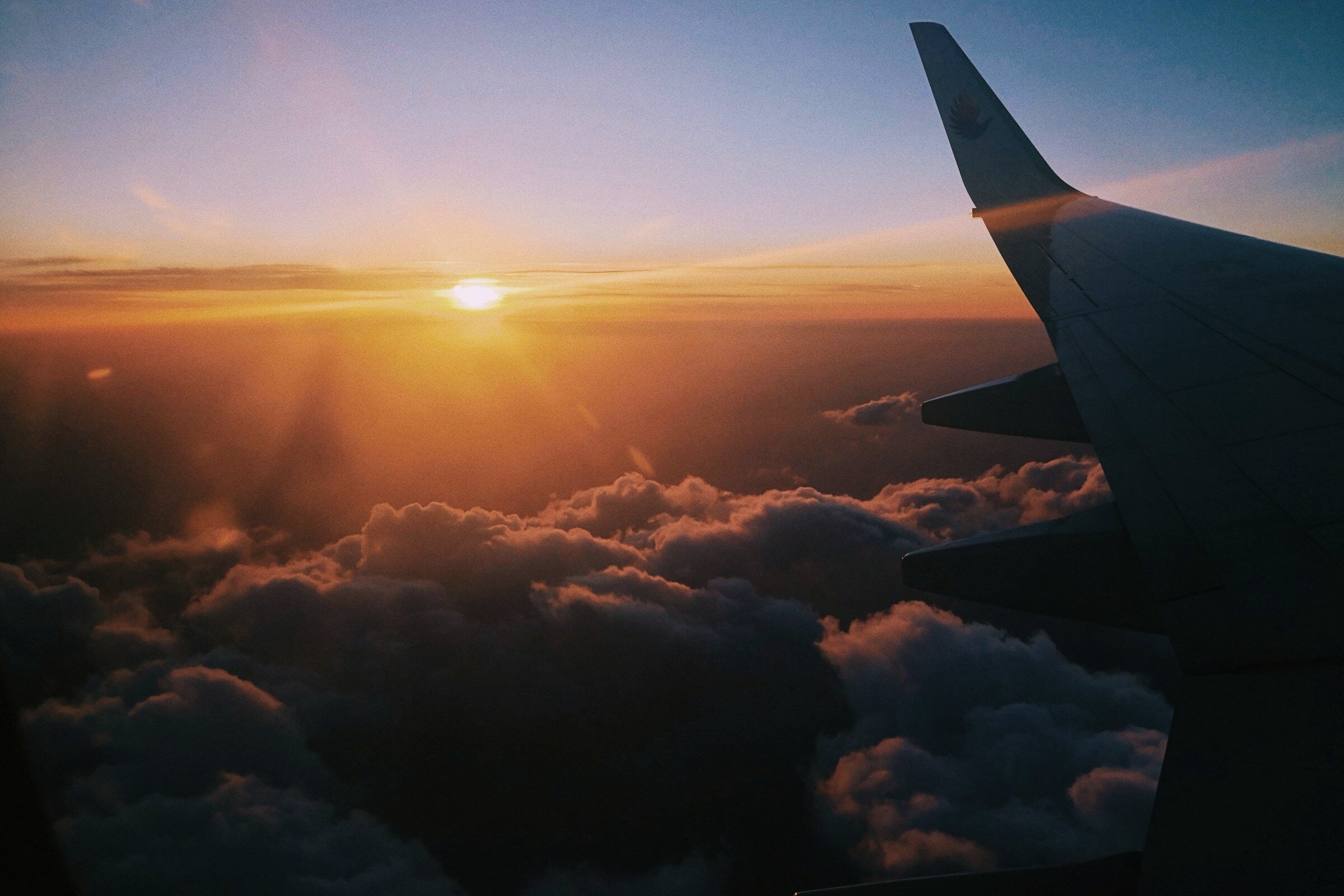 An aircraft wing over sunlit clouds.